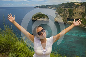 Happy Asian Chinese woman in sunglasses enjoying amazing coast scene from view point at tropical paradise beach with diamond rock