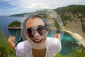 Happy Asian Chinese woman in sunglasses enjoying amazing coast scene from view point at tropical paradise beach with diamond rock