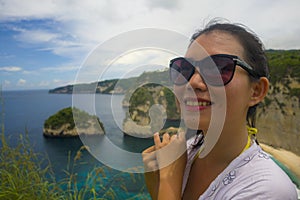 Happy Asian Chinese woman in sunglasses enjoying amazing coast scene from view point at tropical paradise beach with diamond rock