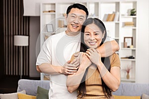 Happy Asian Couple Embracing in Their Cozy Living Room