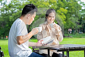 Happy asian couple enjoy,smiling,talk together,wife drink coffee or tea in the morning,husband hold or read a book relax in