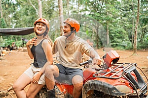 happy asian couple joking while sitting on the atv