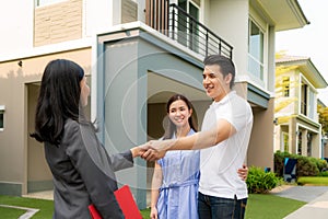 Happy Asian couple looking for their new house and shake hands with real estate broker after a deal. Young couple handshaking real