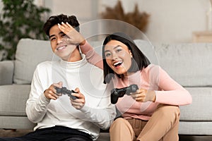 Happy Asian Couple Playing Computer Video Game Sitting At Home
