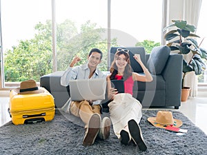 Happy Asian couple ready to trip, young man and woman, showing success, using laptop computer.