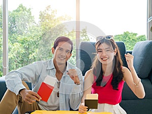 Happy Asian couple ready to trip, young man and woman smile and raising fist and hold and show passport together.