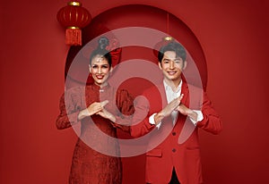 Happy asian couple in red casual attire with gesture of congratulation greeting happy chinese new year 2024