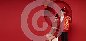 Happy asian couple in red casual attire holding angpao or red packet monetary gift and gold ingot bless with text means great luck