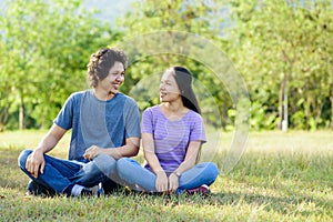 Happy Asian couple sitting on green grass in outdoor