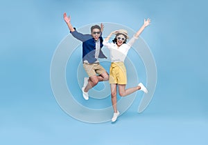Happy Asian couple tourist jumping celebrating to travel on summer holiday isolated on blue background