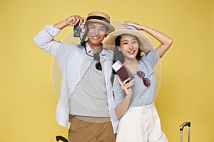 Happy Asian couple tourist photographer with going to travel on holidays taking images photo on camera isolated on yellow