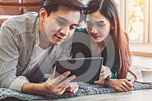 Happy Asian couple use tablet while lying down