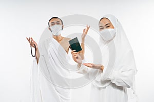 Happy asian couple wearing ihram clothes holding a passport