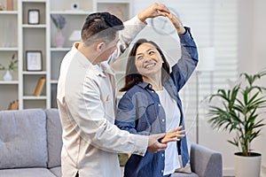 Happy Asian couple, young family man and woman celebrate moving to a new house, buying an apartment. They dance, hug