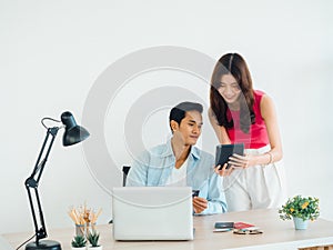 Happy Asian couple, young man and woman using tablet and laptop computer together.