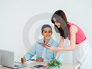 Happy Asian couple, young man and woman using tablet and laptop computer together for flight booking.