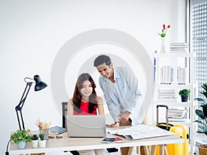 Happy Asian couple, young woman and man using laptop computer and map together.