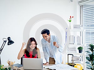 Happy Asian couple, young woman and man using laptop computer together.