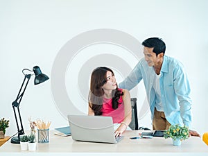 Happy Asian couple, young woman and man using tablet and laptop computer together.