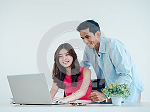 Happy Asian couple, young woman and man using tablet and laptop computer together.