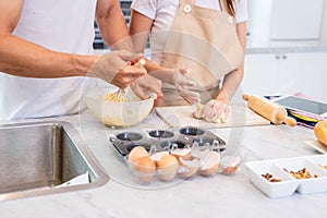 Happy Asian couples cooking and baking cake together in kitchen room. Man and woman looking to tablet follow recipe step at home.