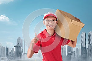 Happy asian courier man carrying cardboard box on the shoulder