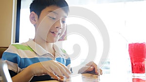 Happy Asian cute boy reading menu book and point .