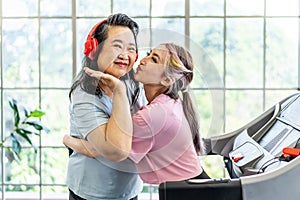 Happy Asian daughter and elderly mother in sportswear exercise together at home both of them smiled happily. Retired woman enjoy