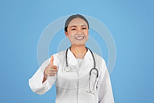 Happy Asian Doctor Woman In Uniform Gesturing Thumb Up At Camera