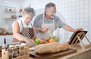 Happy asian elder senior couple cooking fresh meal in kitchen at home