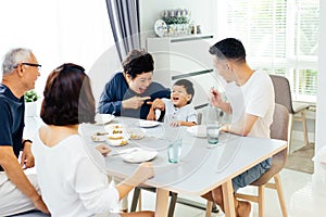 Happy Asian extended family having dinner at home full of laughter and happiness.