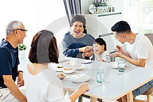 Happy Asian extended family having dinner at home full of laughter and happiness.