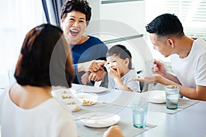 Happy Asian extended family having dinner at home full of laughter and happiness.