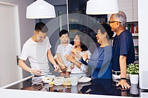 Happy Asian extended family preparing food at home full of laughter and happiness.