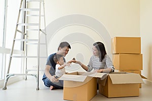 Happy Asian family with cardboard boxes in new house at moving day.