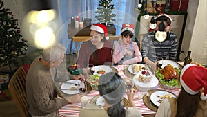 Happy asian family celebrating Christmas together at home. Cheerful senior parents and children in Santa hat