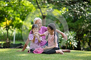 Happy Asian family children having fun and catches a net of insects with her grandfather in the park