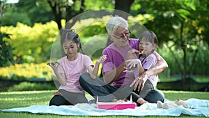 Happy Asian family children having fun and playing with her grandfather in the park