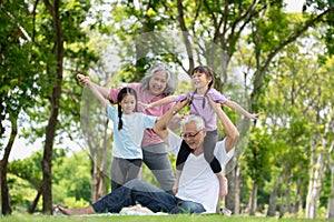 Happy Asian family children having fun and playing with her grandparents in the park