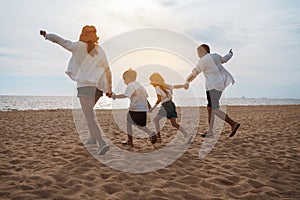 Happy asian family enjoy the sea beach at consisting father, mother,son and daughter having fun playing beach in summer vacation