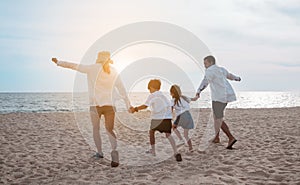 Happy asian family enjoy the sea beach at consisting father, mother,son and daughter having fun playing beach in summer vacation