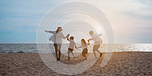 Happy asian family enjoy the sea beach at consisting father, mother,son and daughter having fun playing beach in summer vacation