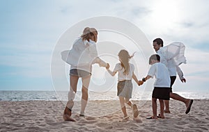 Happy asian family enjoy the sea beach at consisting father, mother,son and daughter having fun playing beach in summer vacation