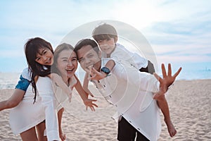 Happy asian family enjoy the sea beach at consisting father, mother,son and daughter having fun playing beach in summer vacation