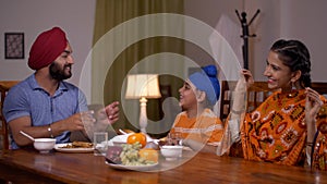 Happy Asian family enjoying at the lunch table - singing cheerfully. Sikh Indian Family at Home
