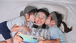 Happy Asian family enjoying with smartphone at cozy home. Smiling mother and cute daughters using phone, Take a selfie or video cl