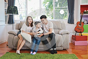 Happy Asian family, father, mother and son playing virtual reality goggles on the sofa in the living room with happy smiling face