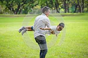 happy asian Family .Father and son having fun playing and stretching out hands  pretending flying  together in the park .dad photo
