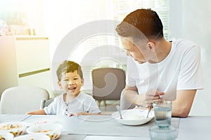 Happy Asian family of father and son playing and laughing while having dinner.