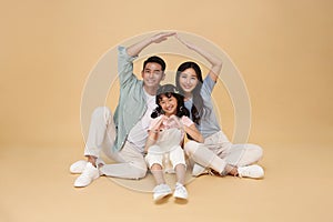 Happy asian family forming house roof with their hands at home. Insurance concept.